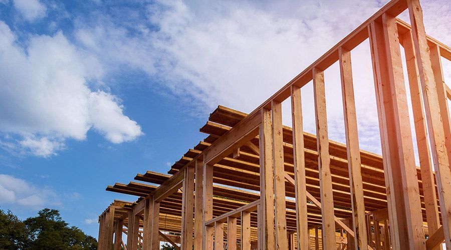 A house is being built with wooden beams and a blue sky in the background.