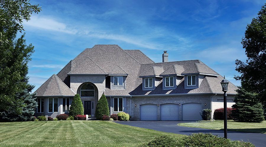 A large house with a gray roof and white garage doors