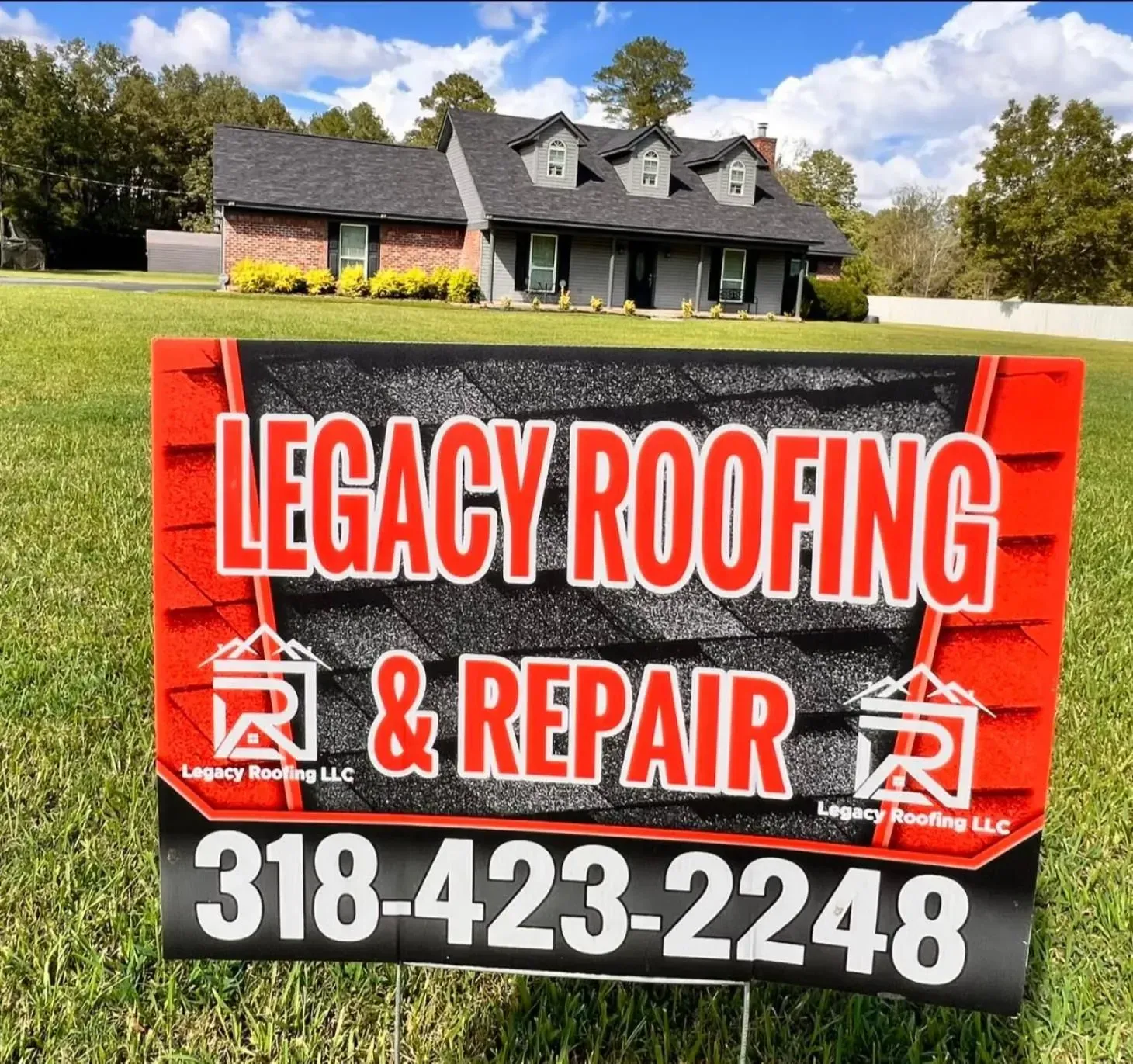 A sign for legacy roofing and repair is in front of a house