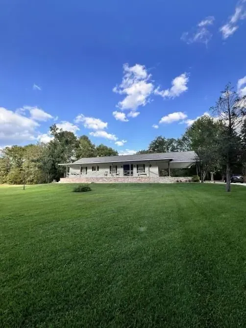 A house is sitting in the middle of a lush green field.