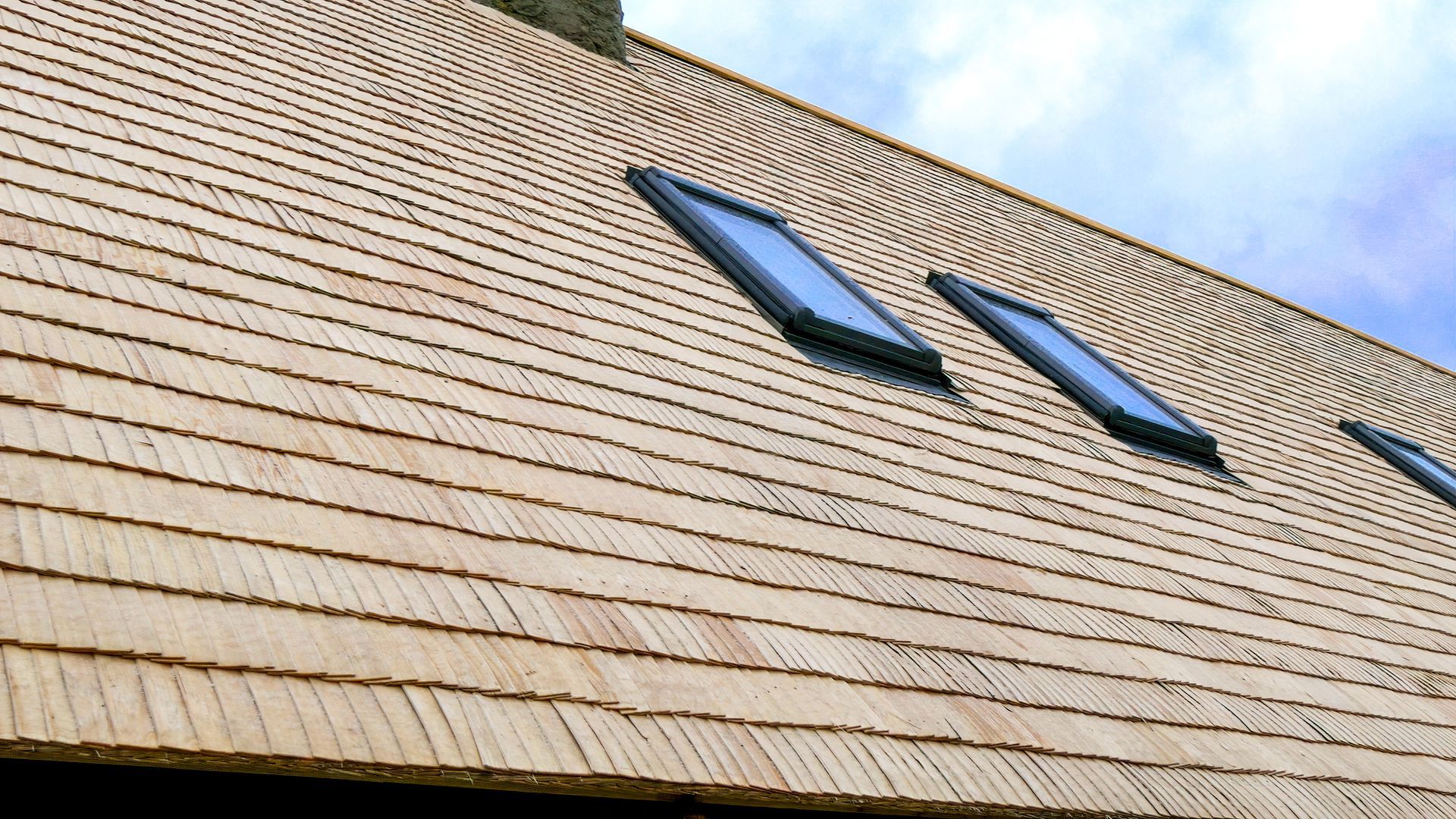 A wooden roof with three skylights on it