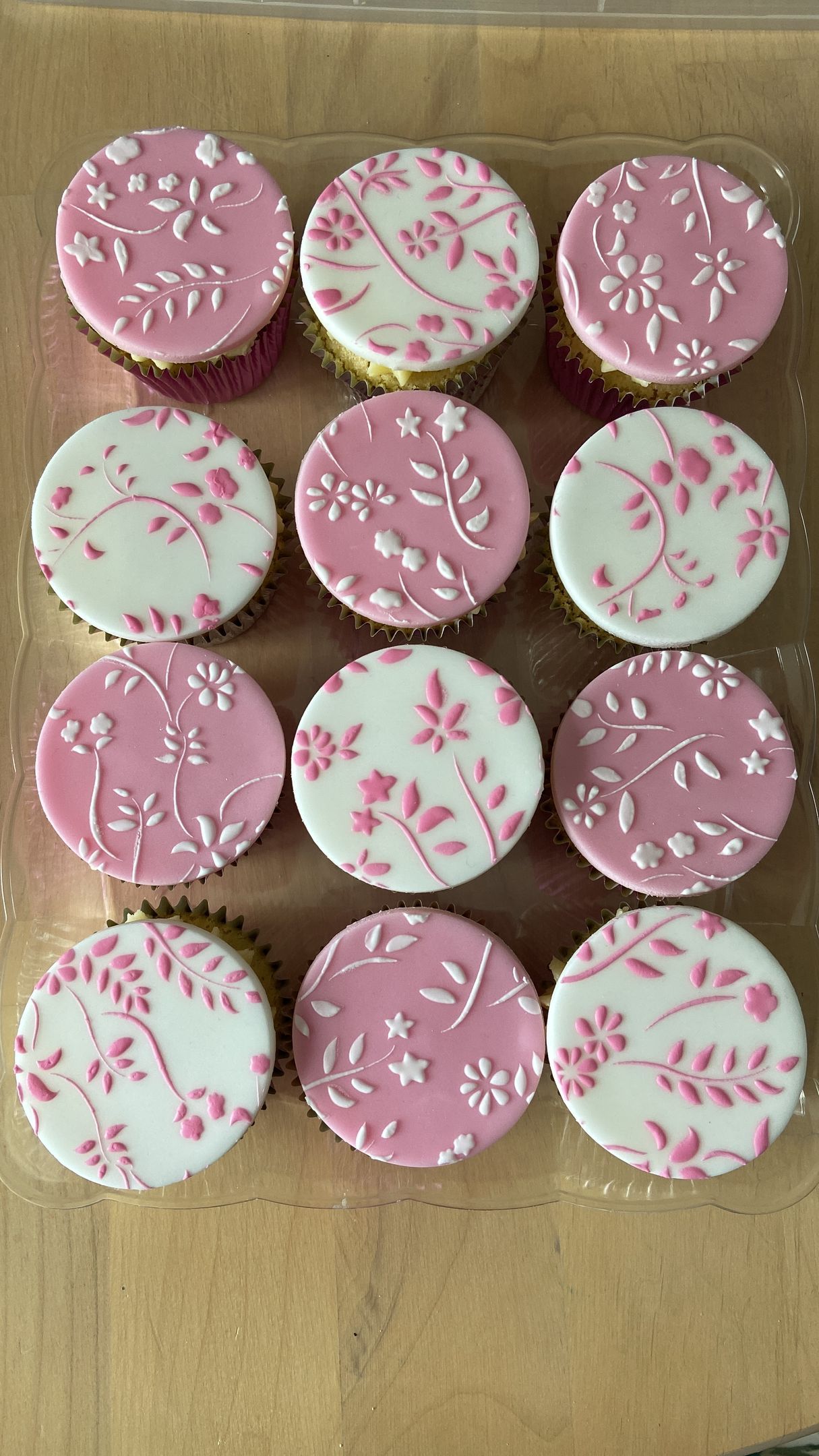 A bunch of pink and white cupcakes on a table.