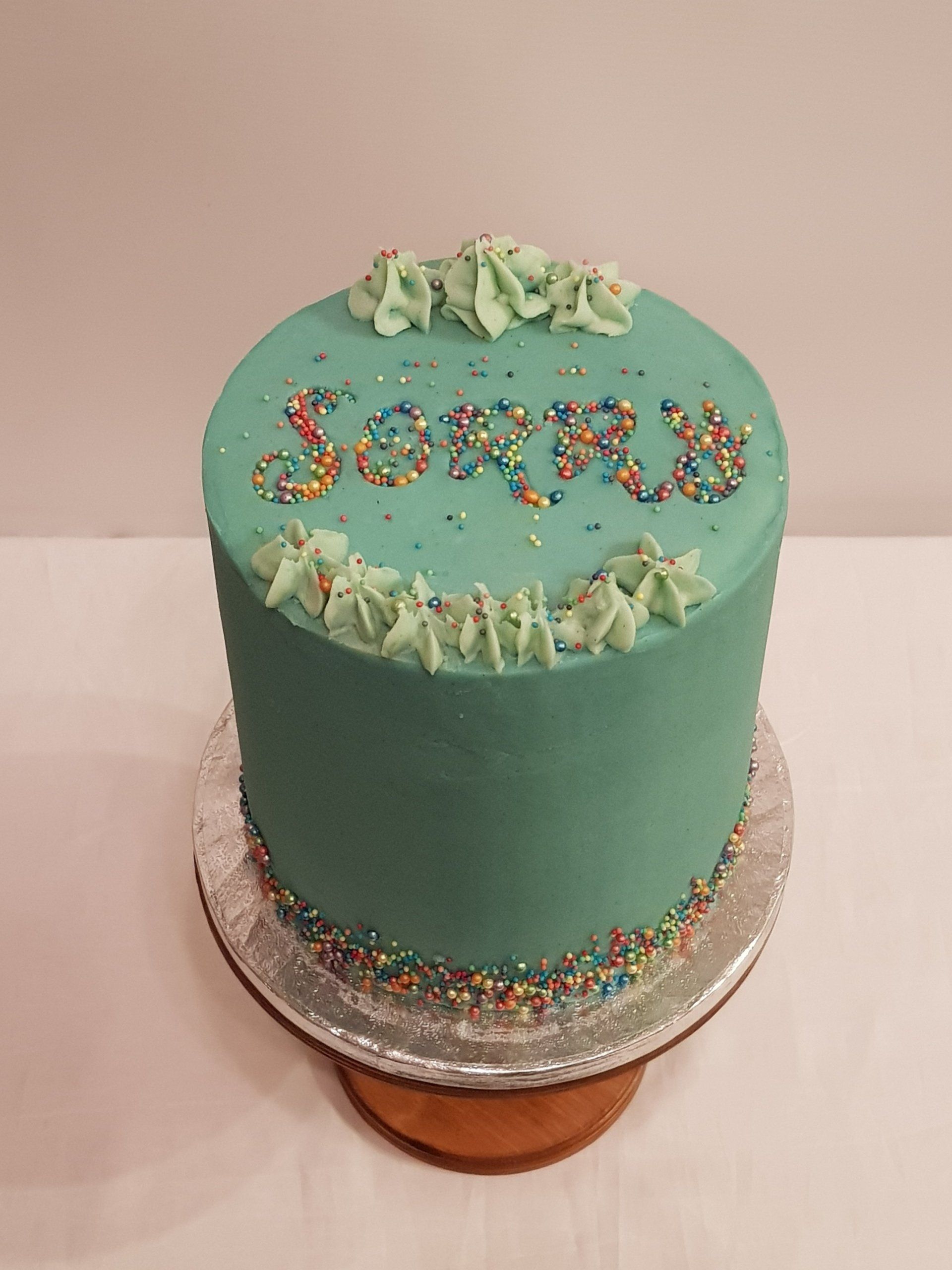 A green cake with the word sorry on it