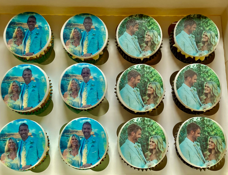A box of cupcakes with pictures of a bride and groom on them