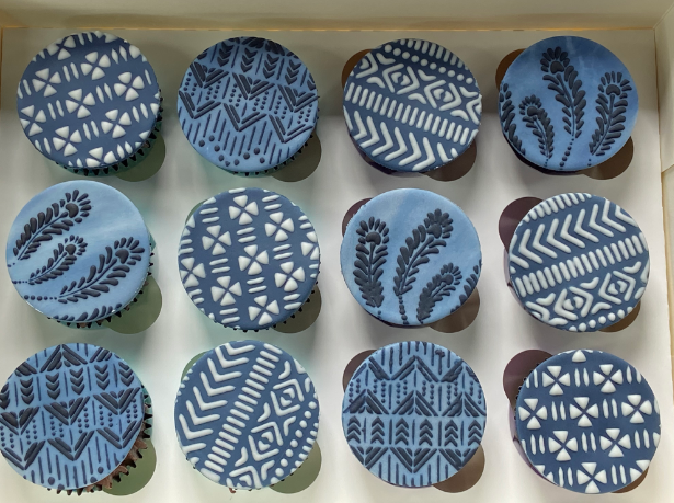 A tray of cupcakes with blue and white patterns on them