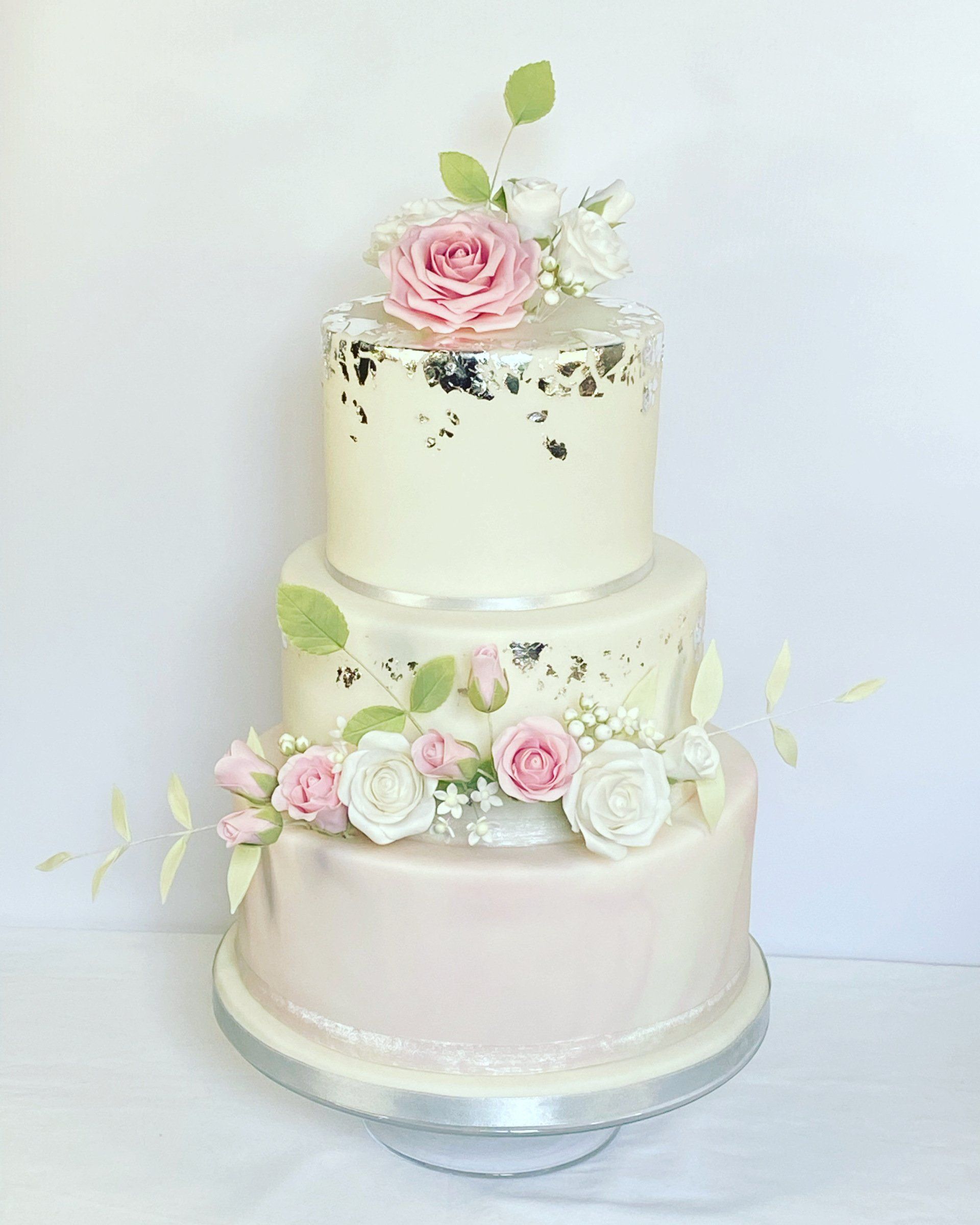 A three tiered wedding cake with pink and white flowers on top.