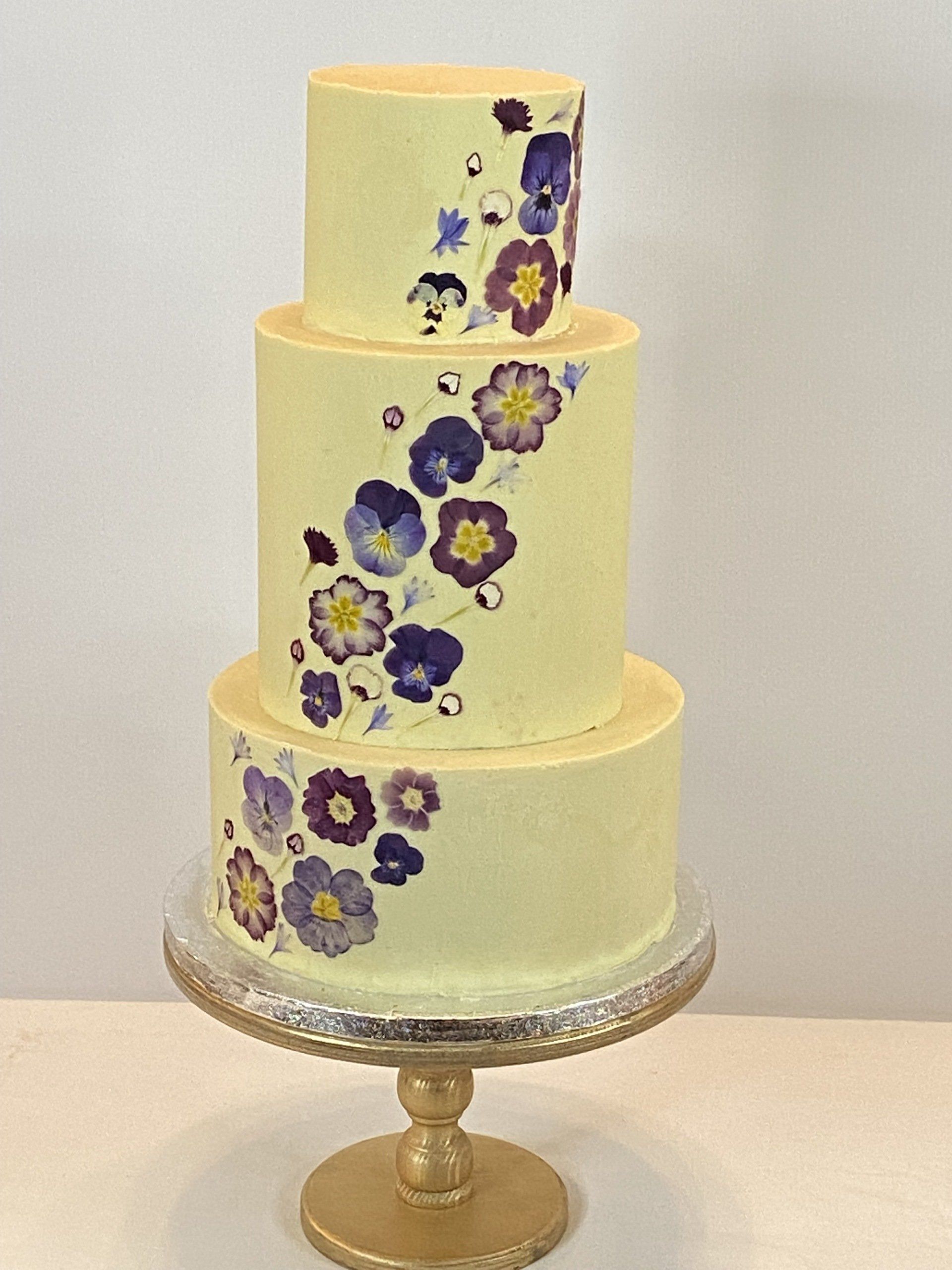 A three tiered cake with purple flowers on it