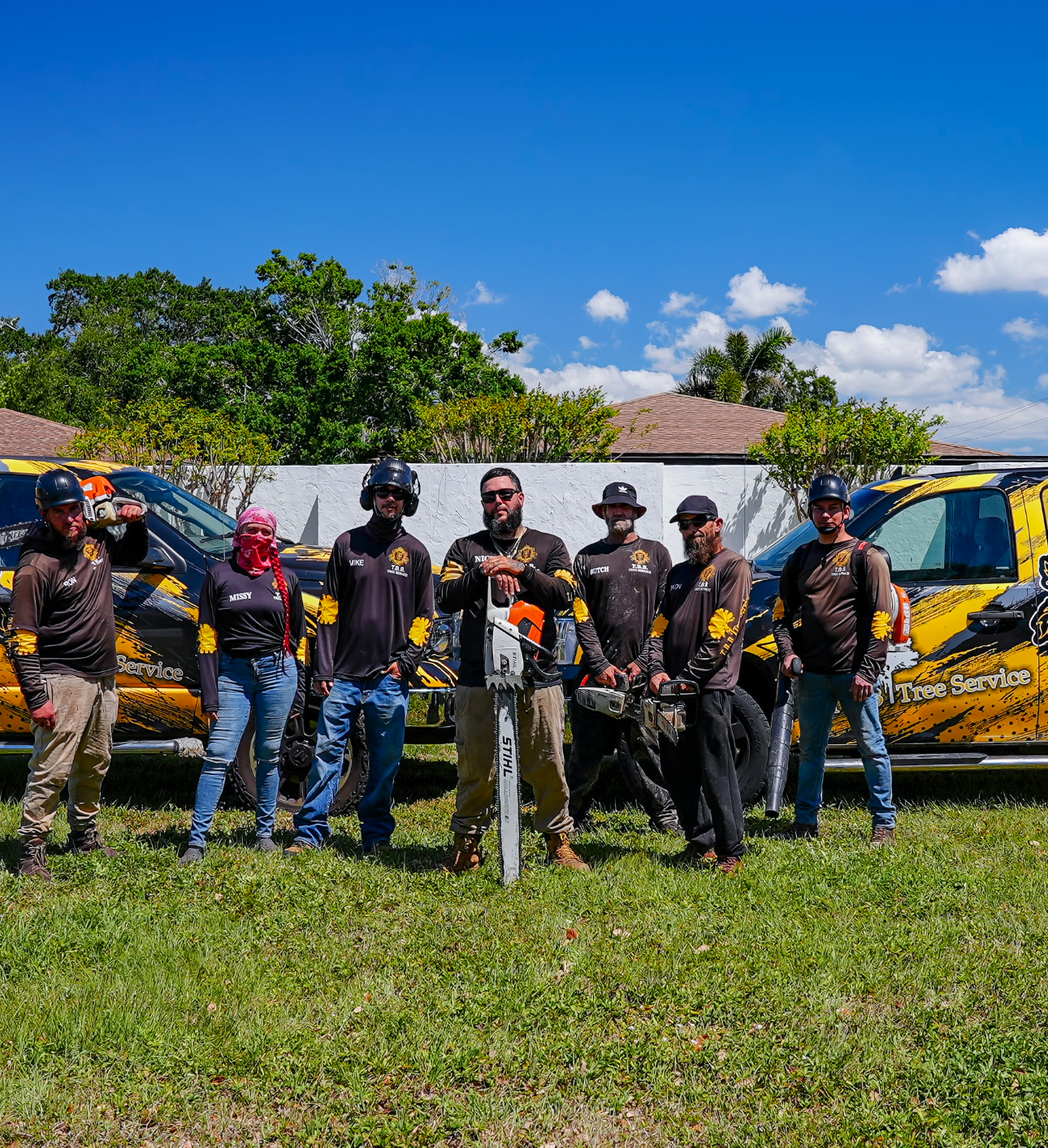 A group of men are standing in a field holding chainsaws.