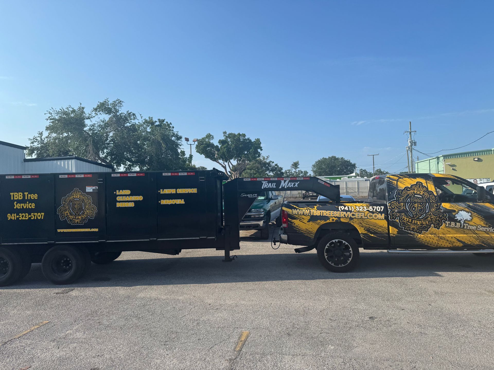 A yellow truck is parked next to a black trailer.