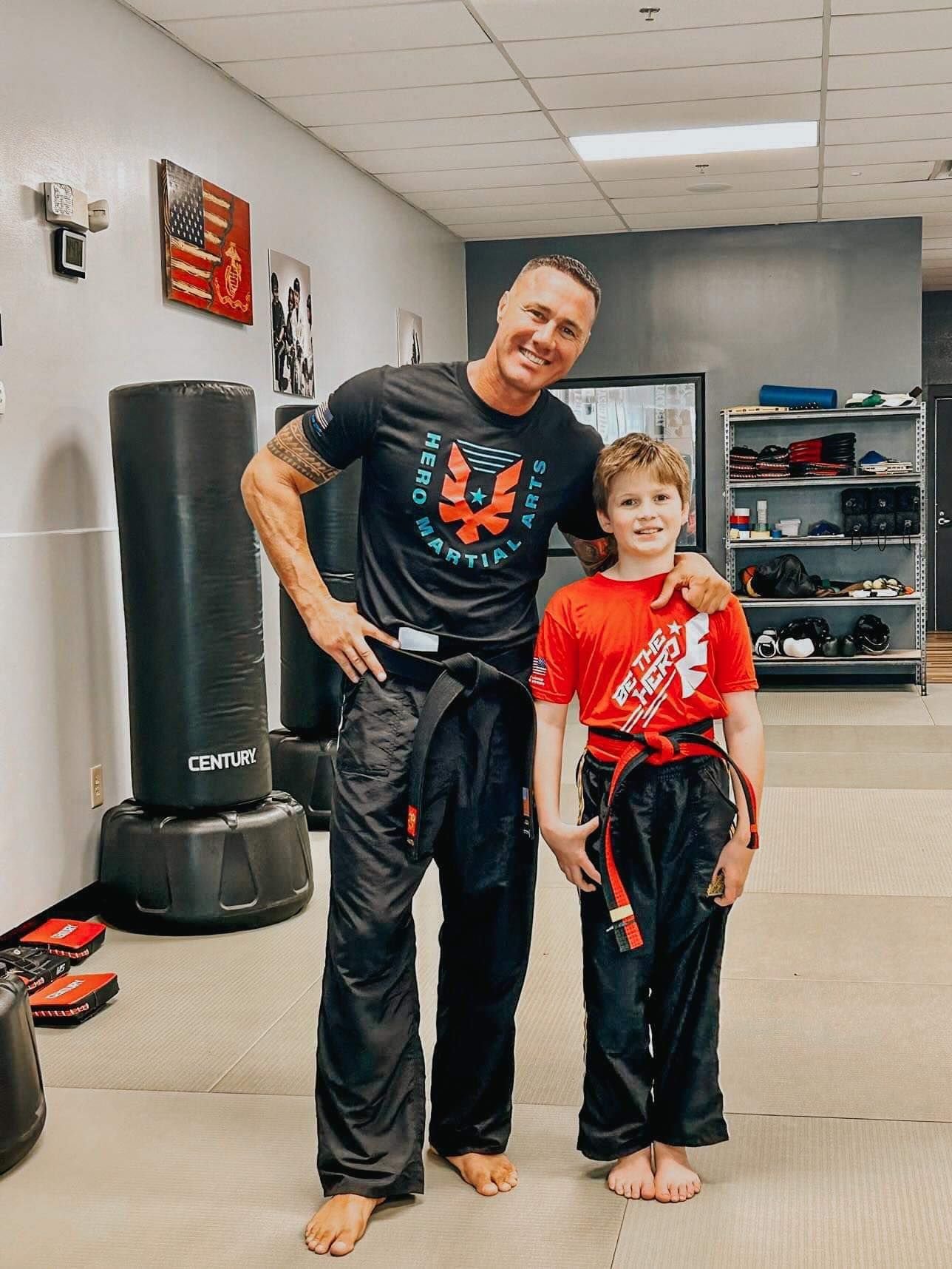 A man and a boy are posing for a picture in a gym.