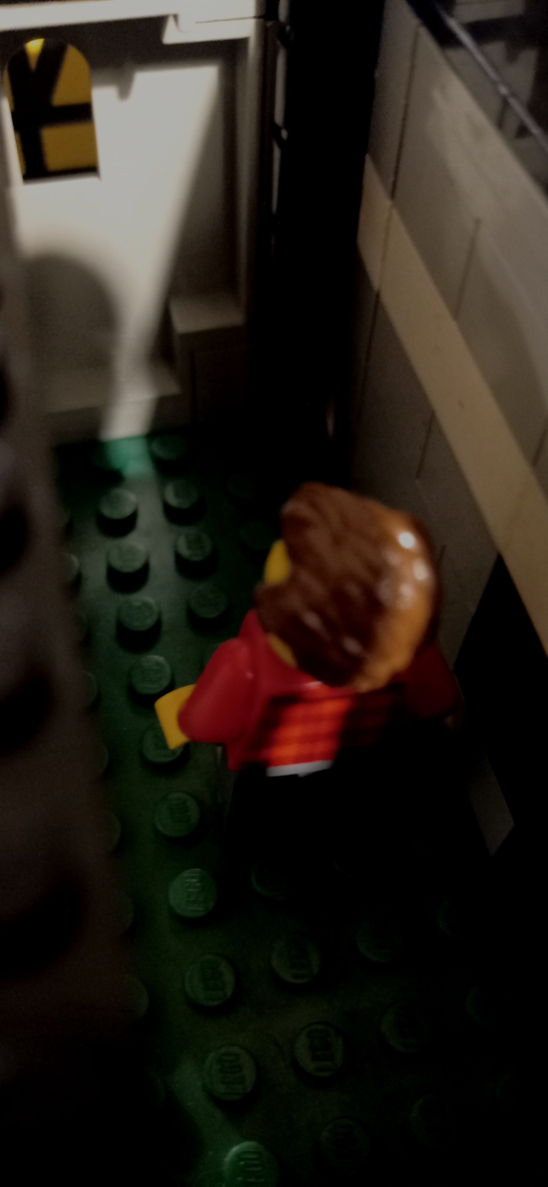 A lego figure is sitting on a green floor