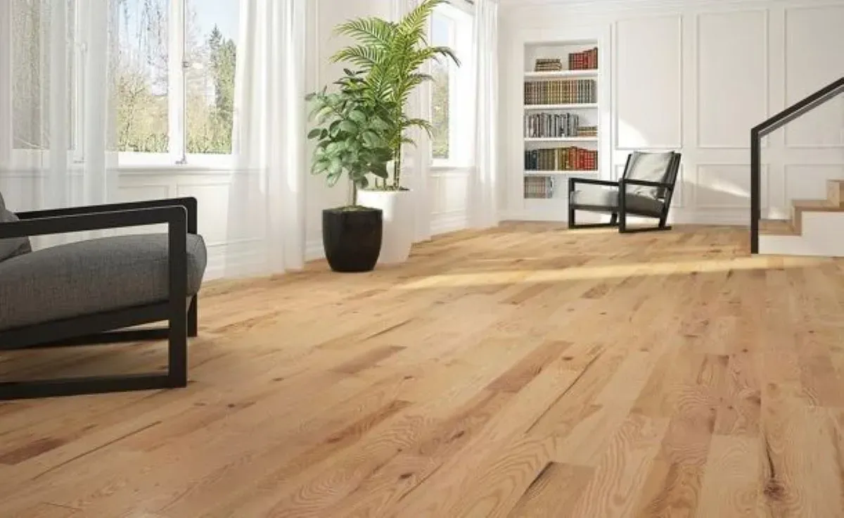 A living room with a wooden floor , chairs , and stairs.