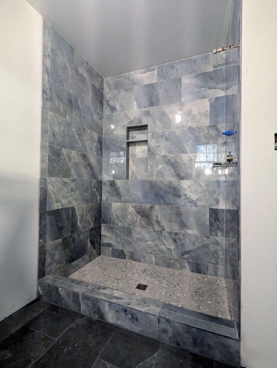 A bathroom with a walk in shower and blue tile walls.