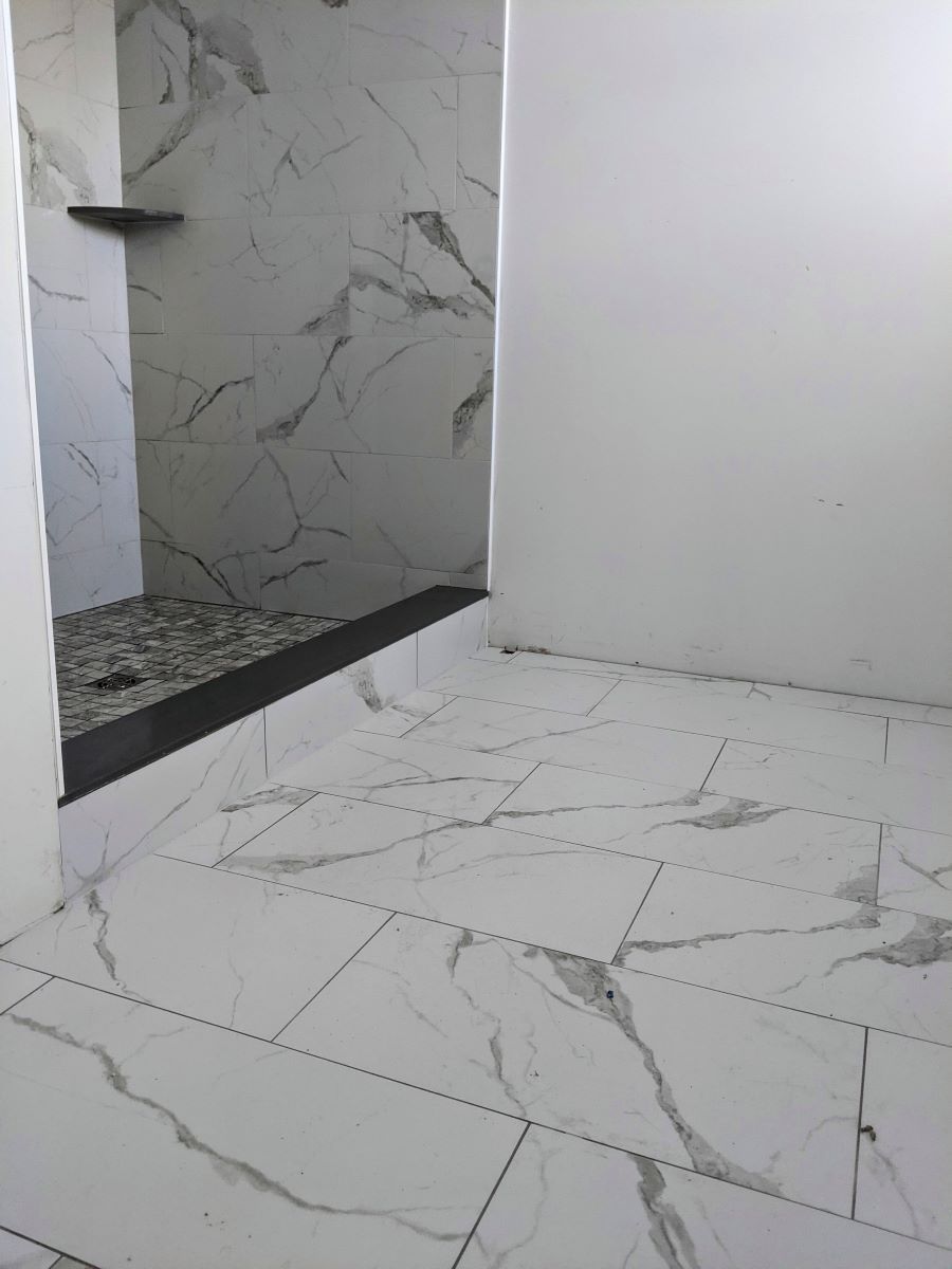 A bathroom with white tiles and a walk in shower.