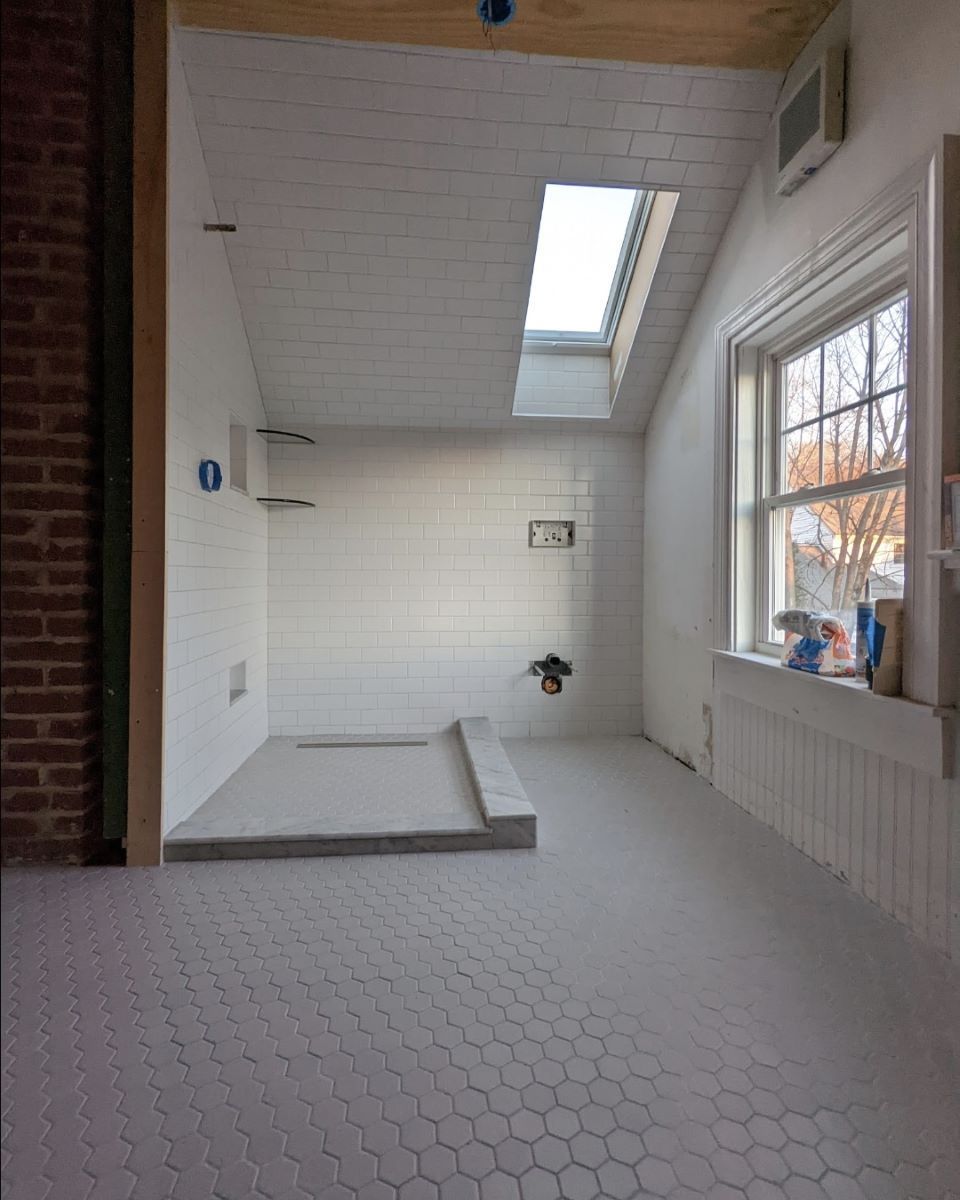 A bathroom with white tiles and a skylight
