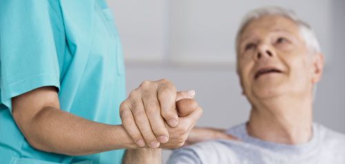 nurse holding the had of an elder man suffering from dementia