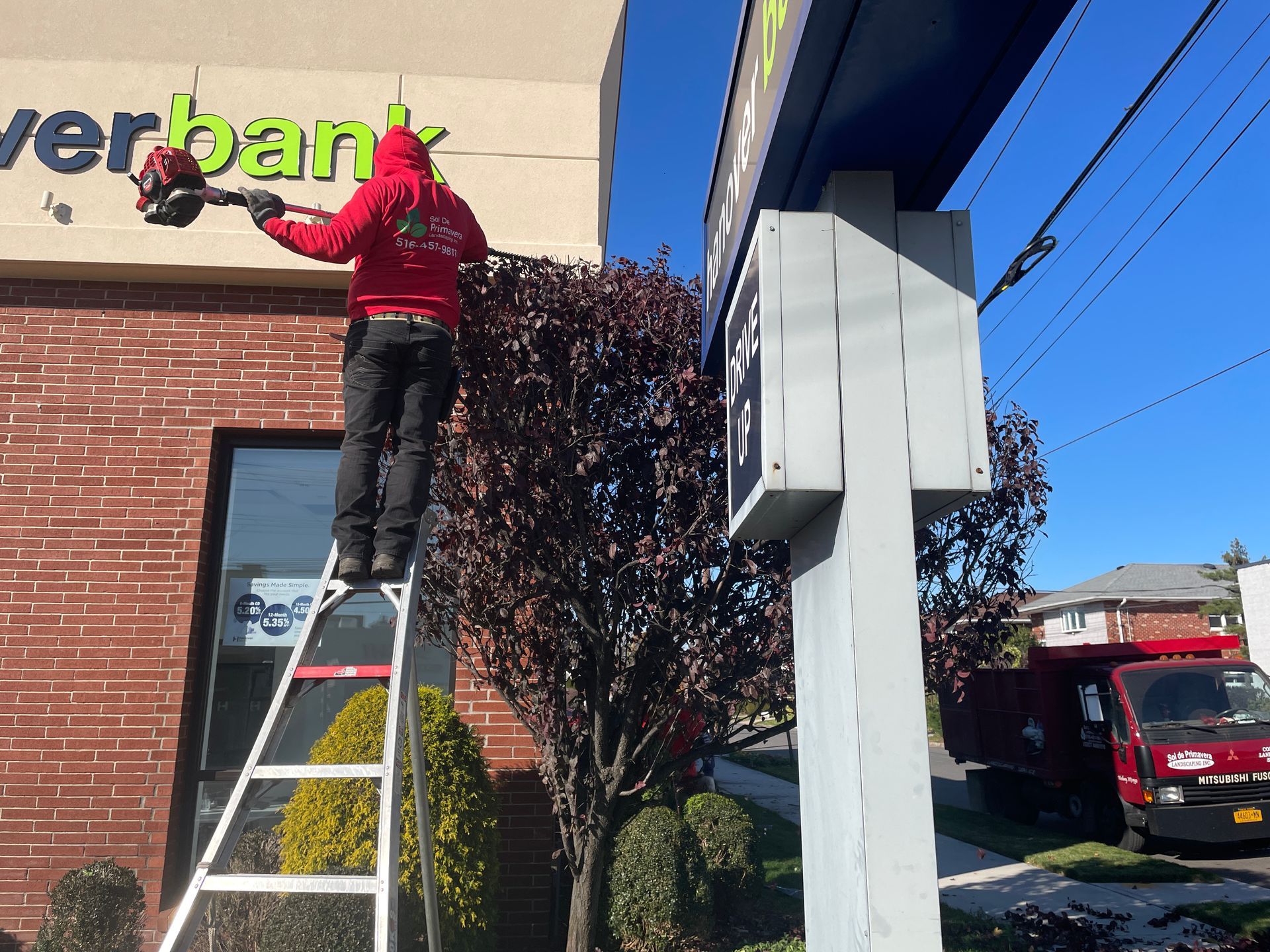 A man on a ladder is painting a sign that says verbank
