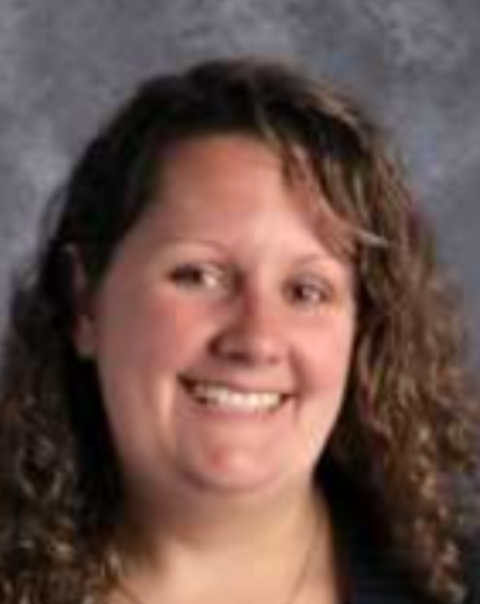 A woman with curly hair is smiling for the camera.