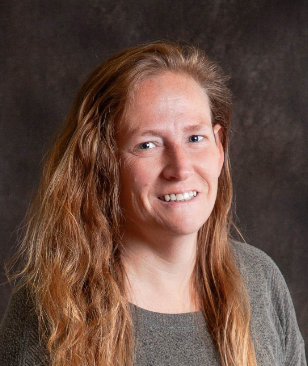 A woman with long red hair is smiling for the camera