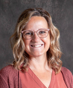 A woman wearing glasses and a red shirt is smiling for the camera.