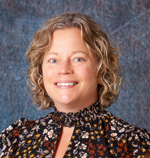 A woman in a blue shirt is smiling for the camera