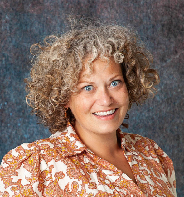 A woman with curly hair is smiling for the camera