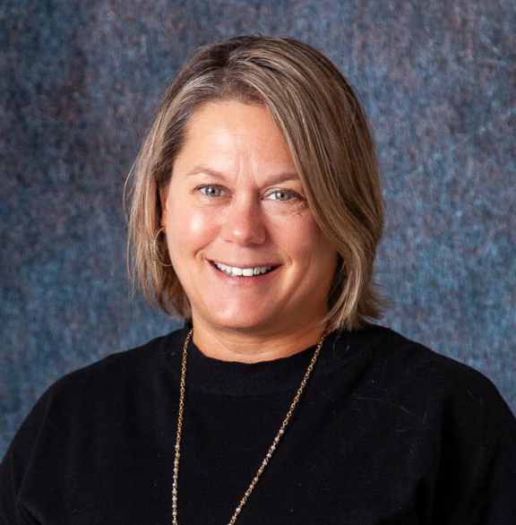 A woman in a green shirt is smiling for the camera.