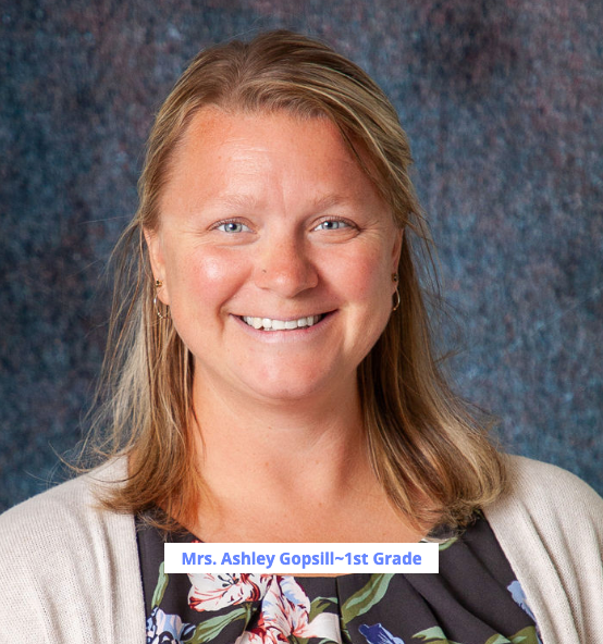 A woman wearing a blue shirt and a grey cardigan smiles for the camera