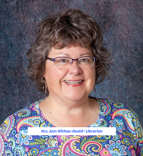A woman wearing glasses and earrings is smiling for the camera