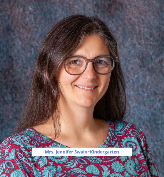 A woman wearing glasses and a white sweater smiles for the camera