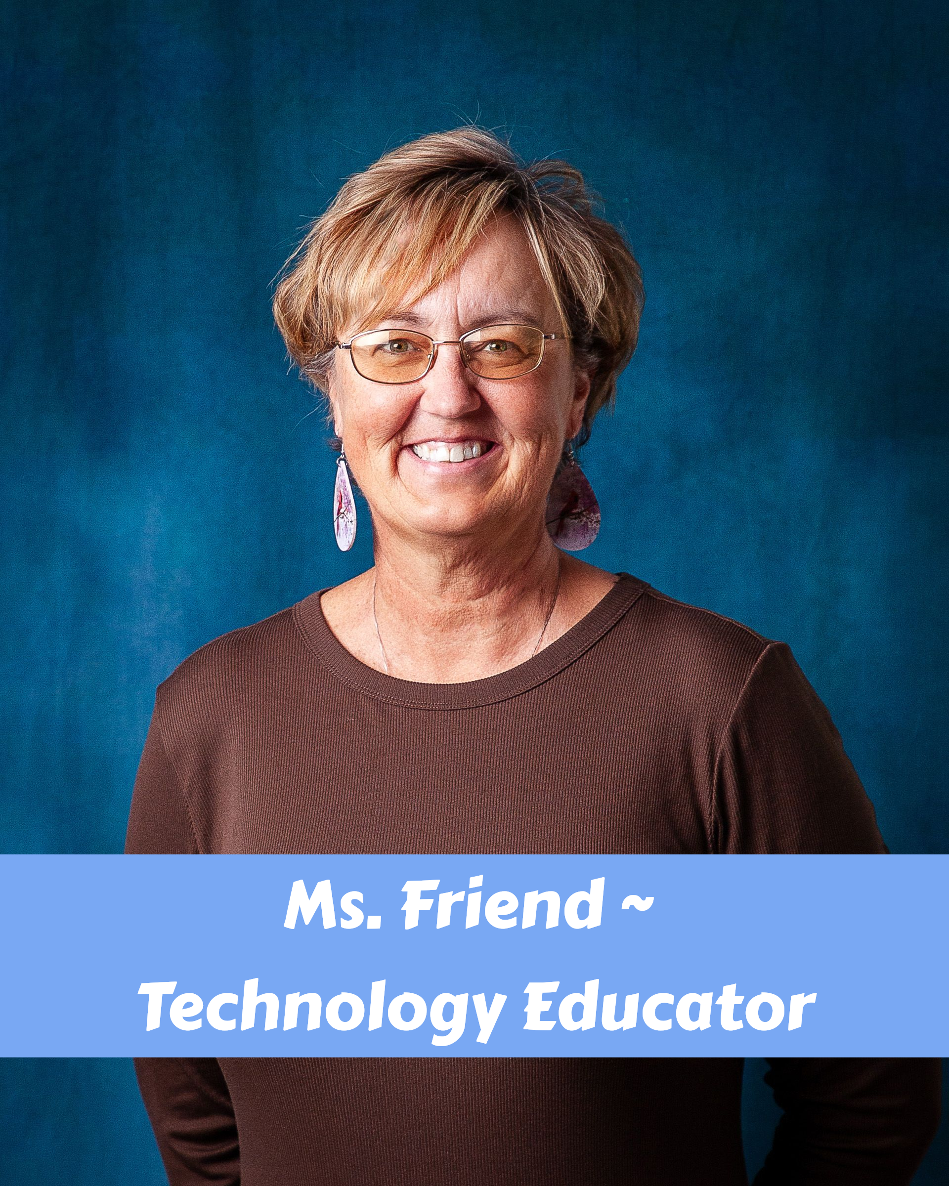 A woman wearing glasses and a dragonfly necklace smiles for the camera