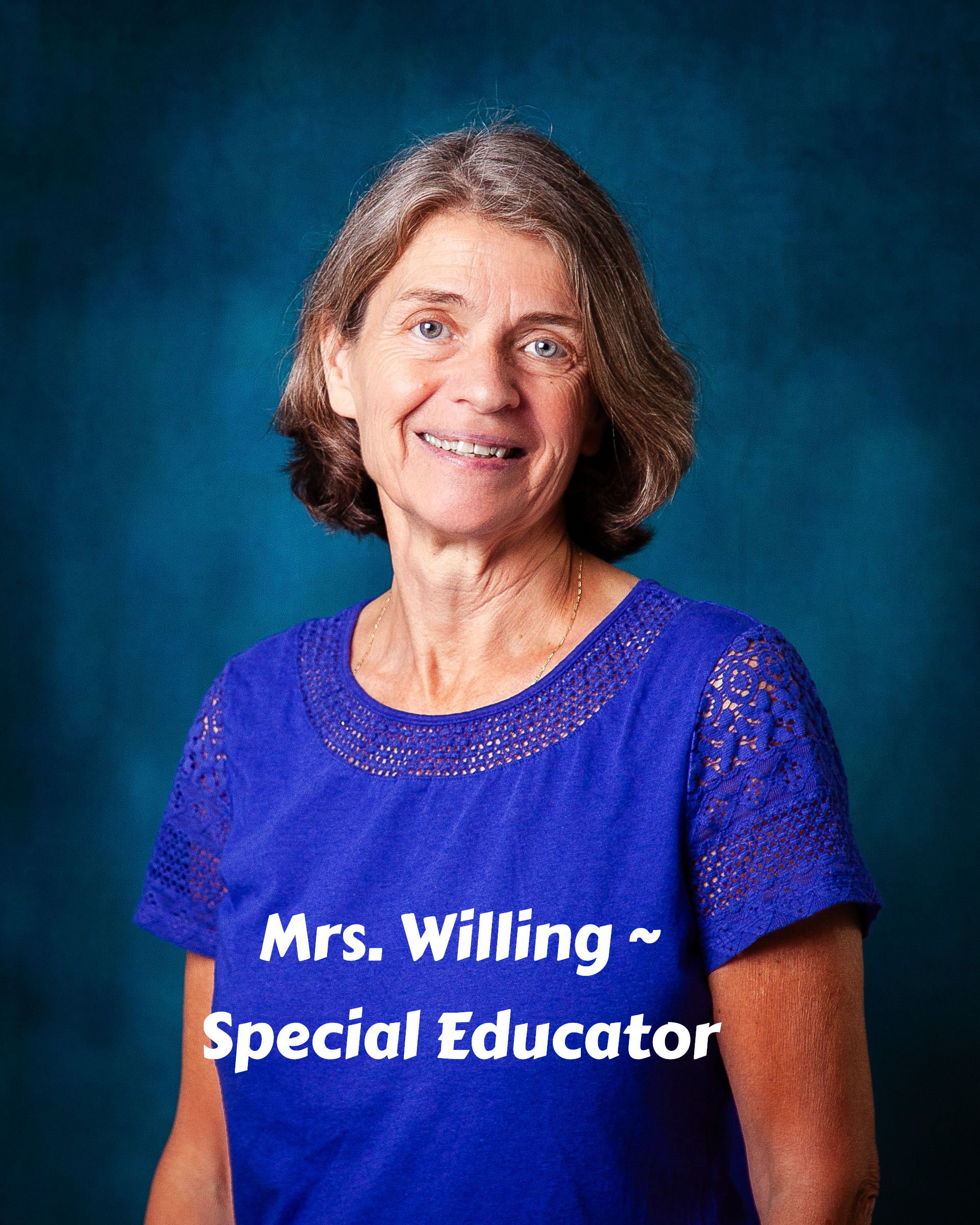 A woman wearing a blue shirt and a black vest smiles for the camera