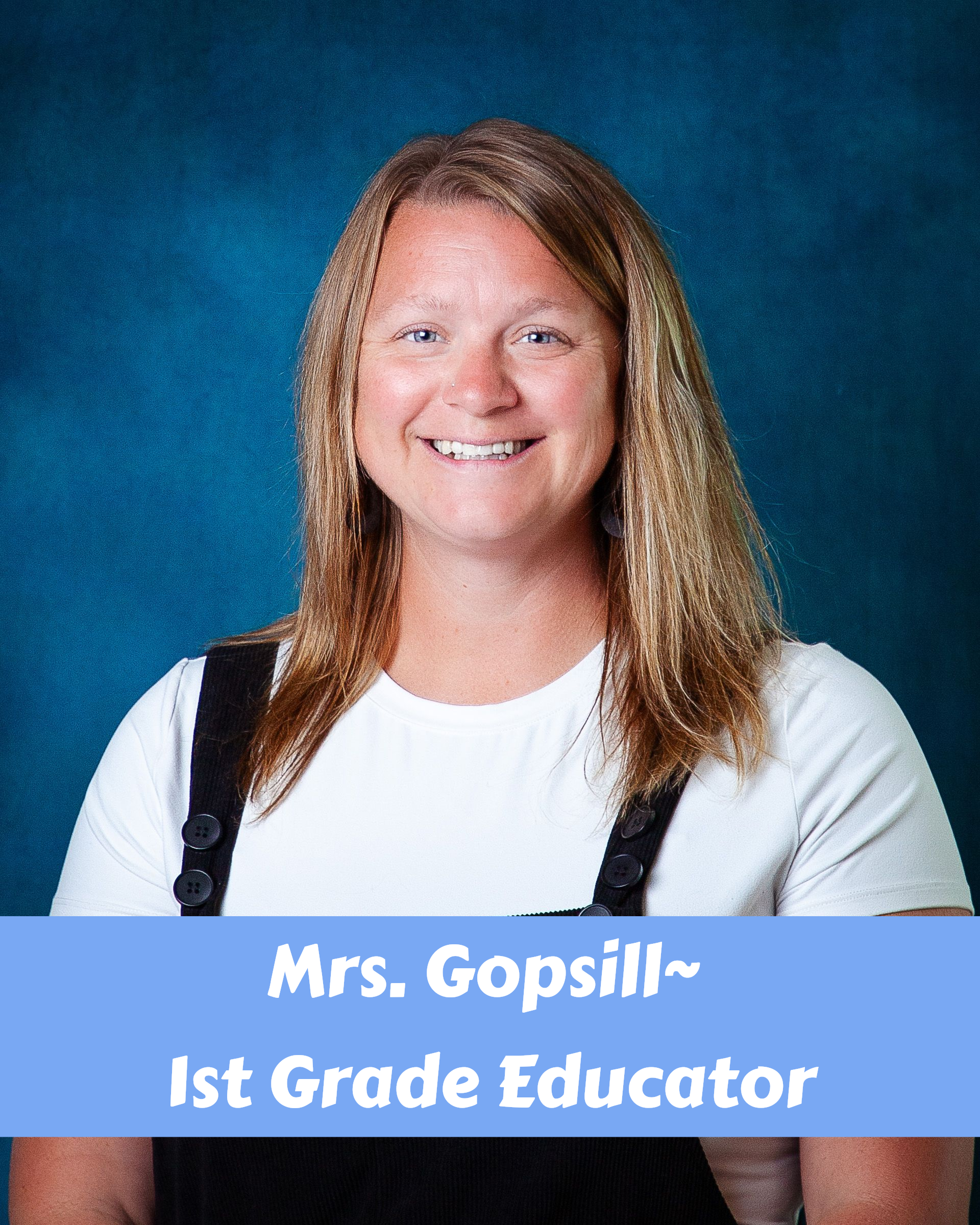 A woman wearing a blue shirt and a grey cardigan smiles for the camera