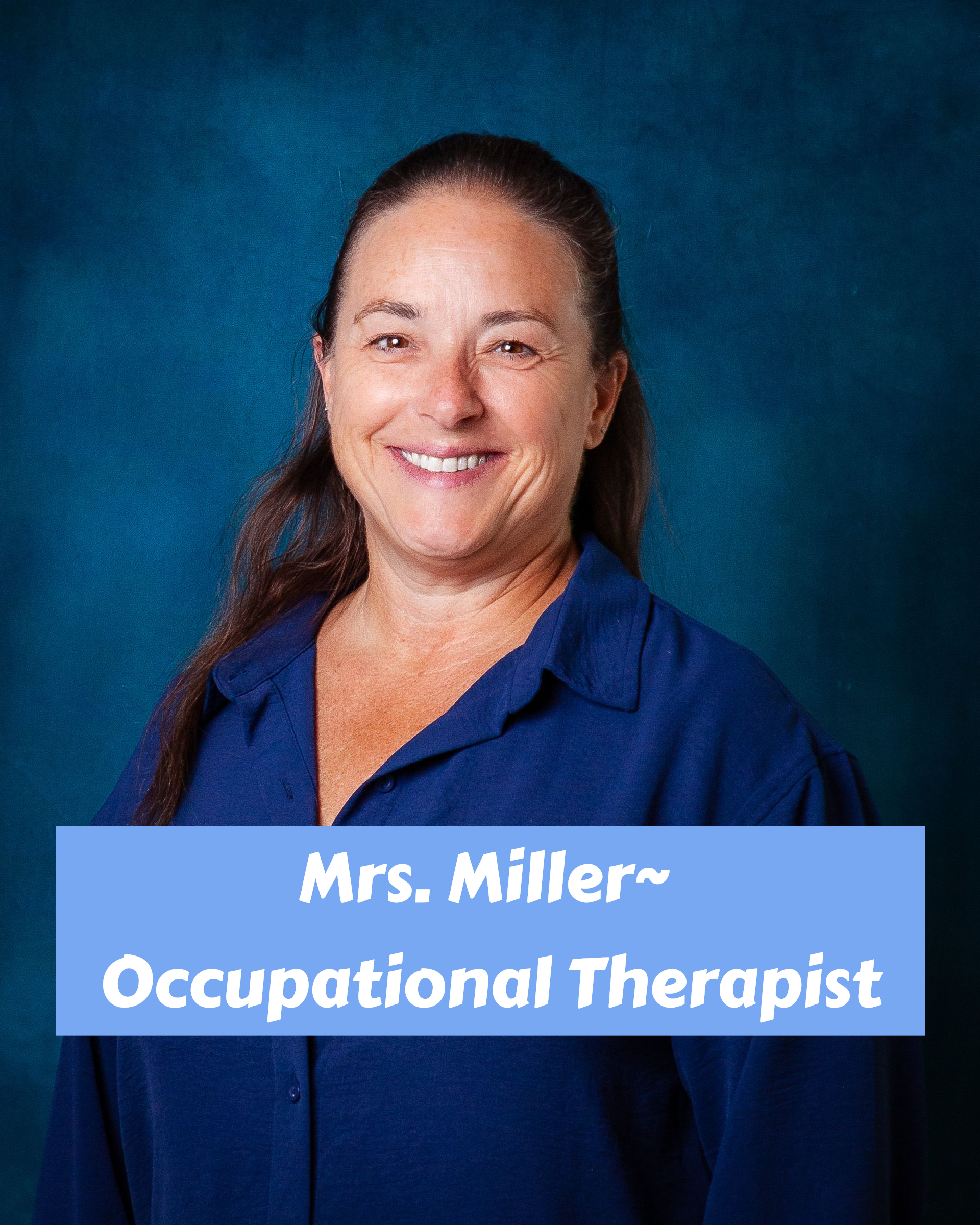 A woman wearing a blue shirt and a necklace is smiling for the camera.