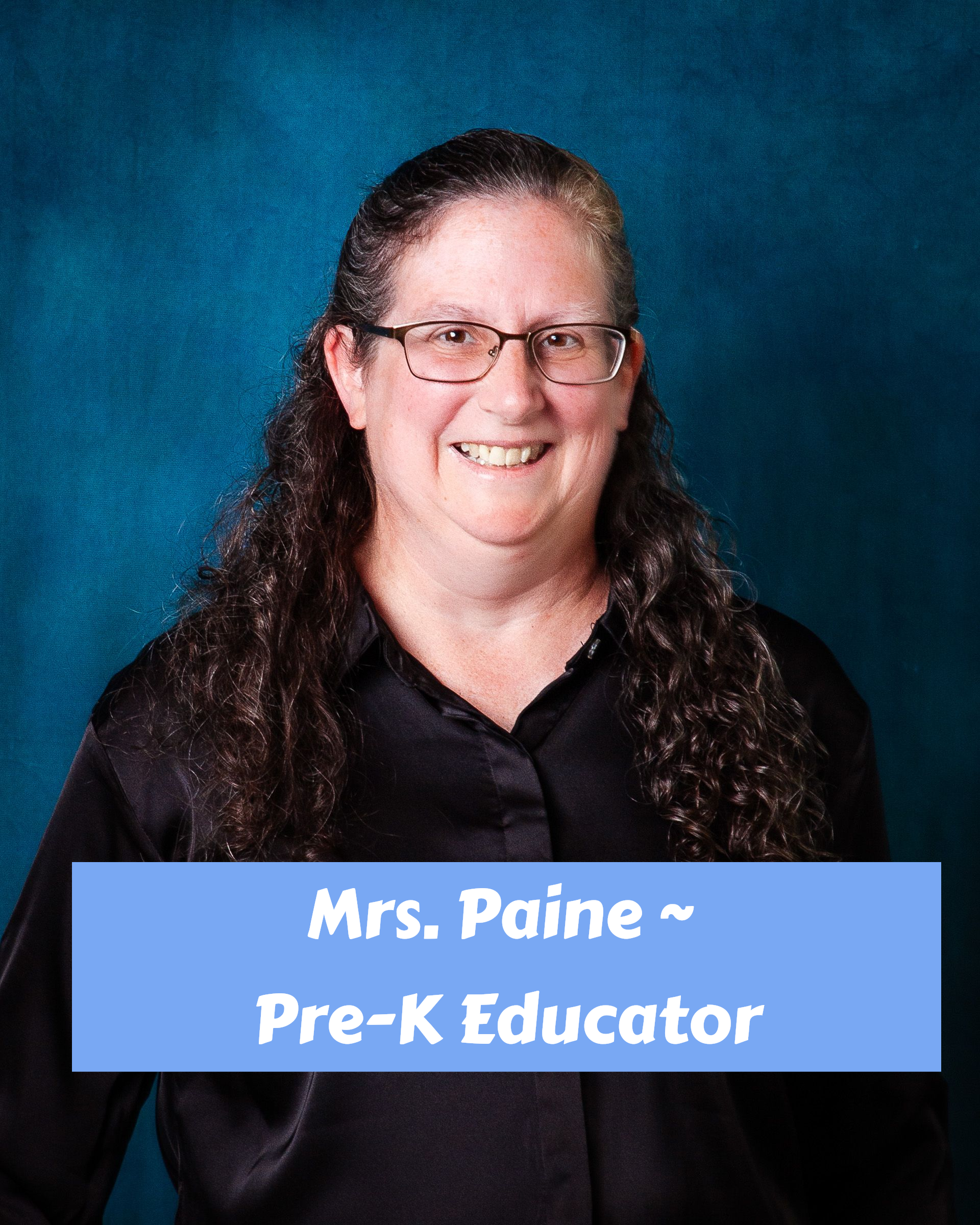 A woman wearing glasses and a purple sweater is smiling for the camera.