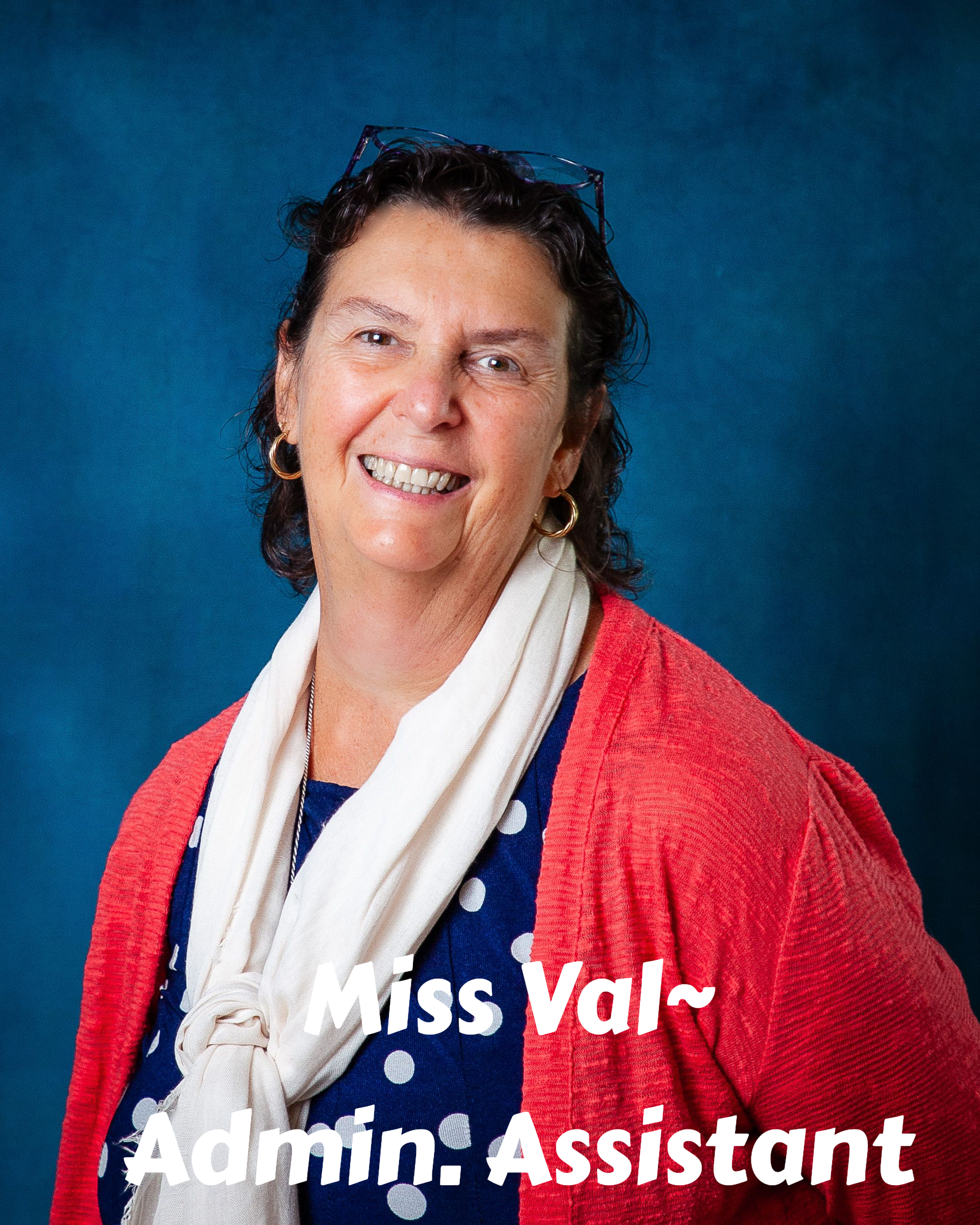 A woman wearing glasses and a floral shirt is smiling