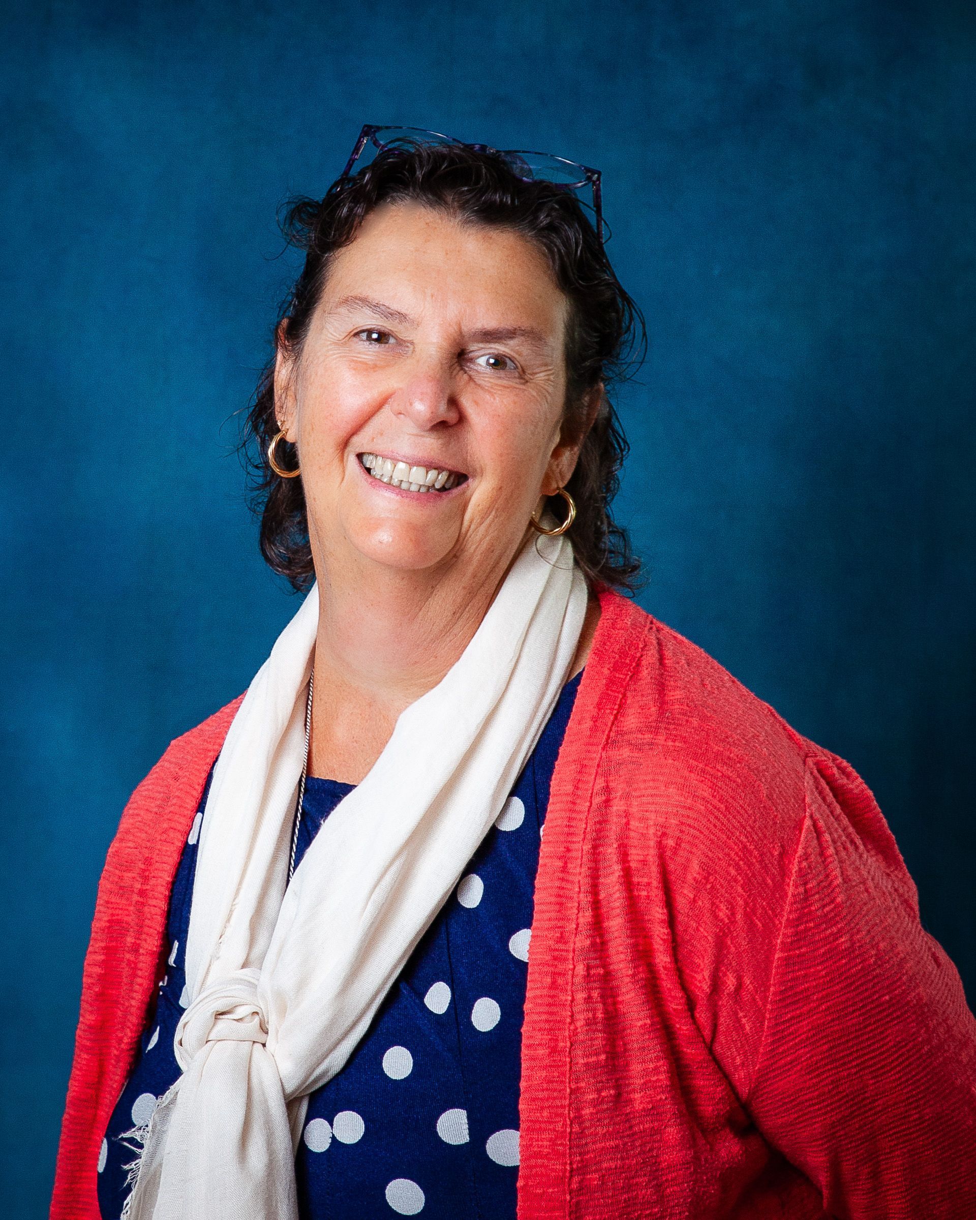 A woman wearing glasses and a floral shirt is smiling