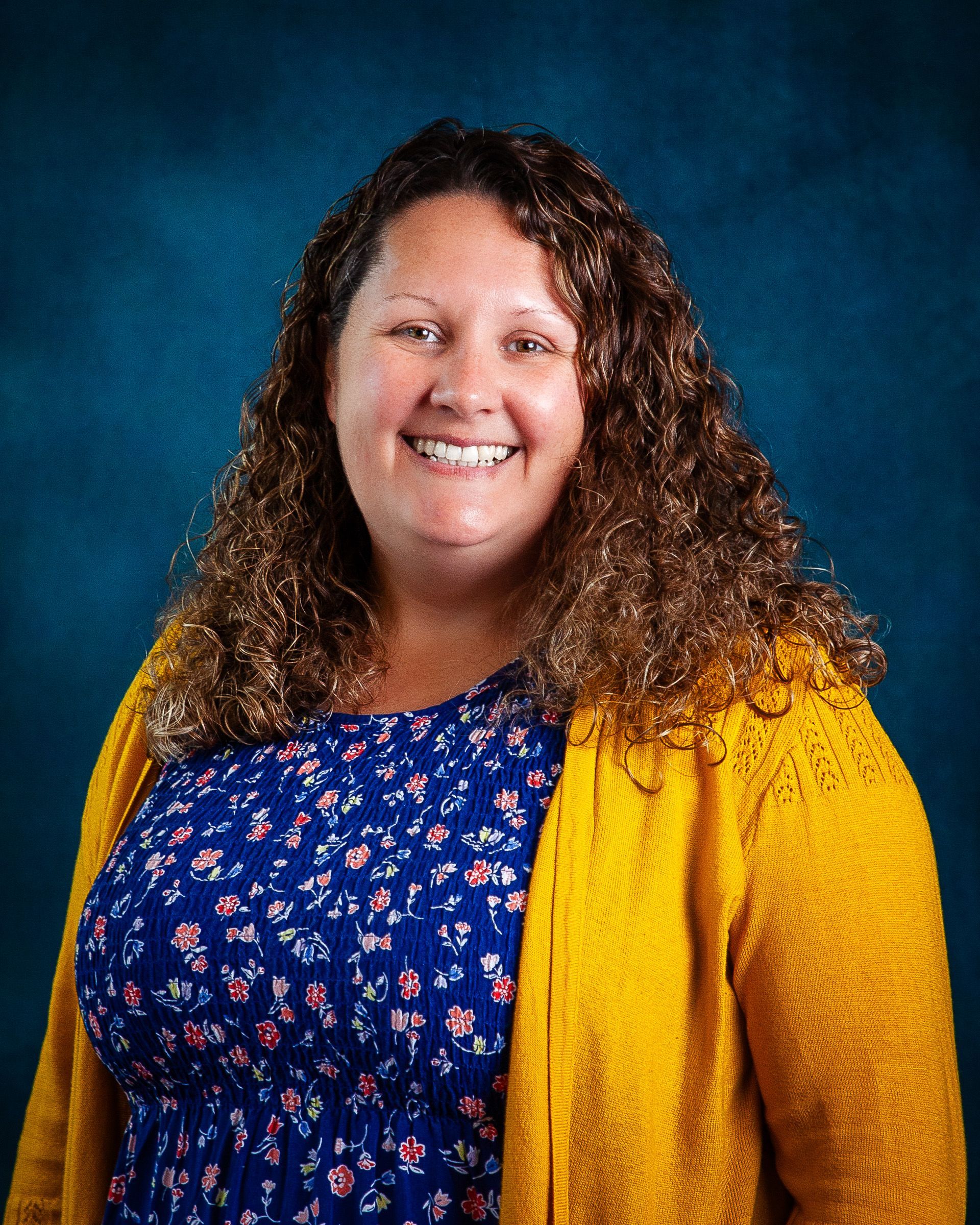A woman with curly hair is smiling for the camera.