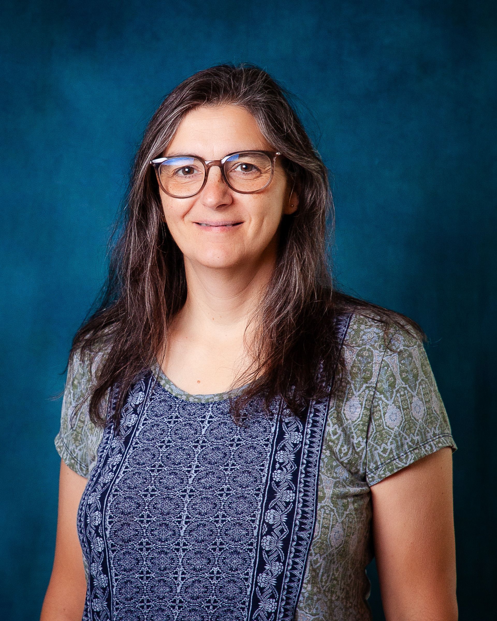 A woman wearing glasses and a white sweater smiles for the camera