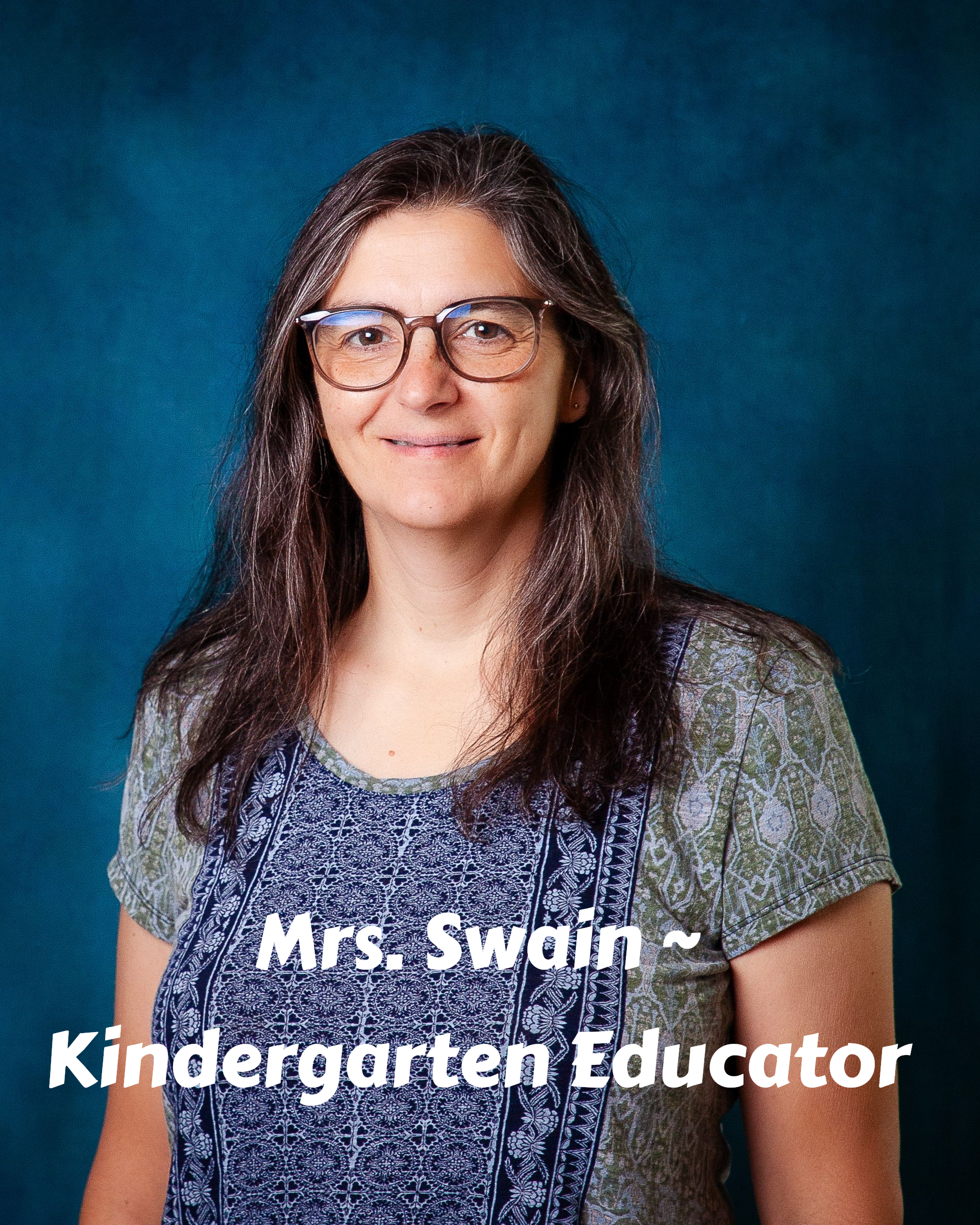 A woman wearing glasses and a white sweater smiles for the camera