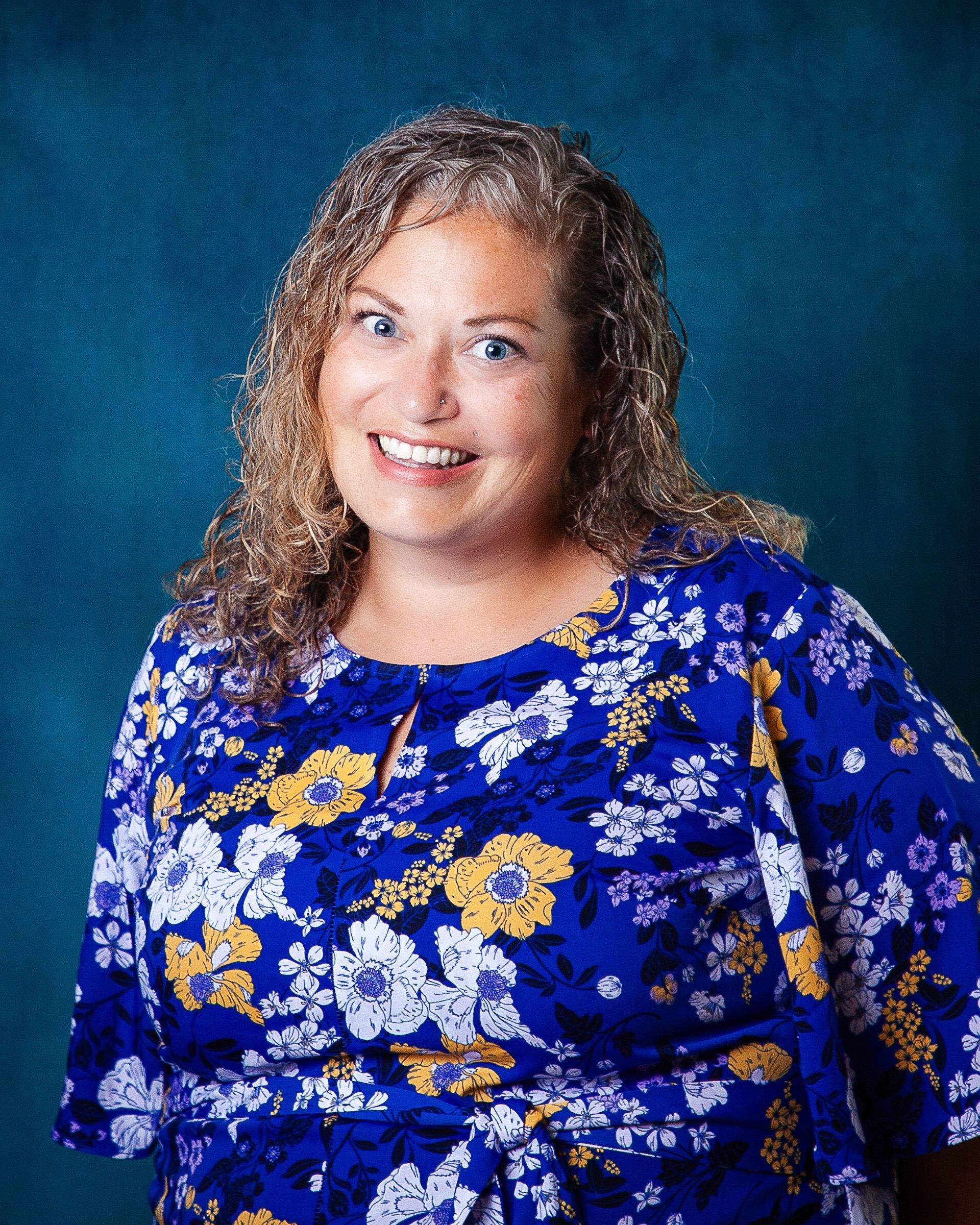 A woman with curly hair is smiling for the camera