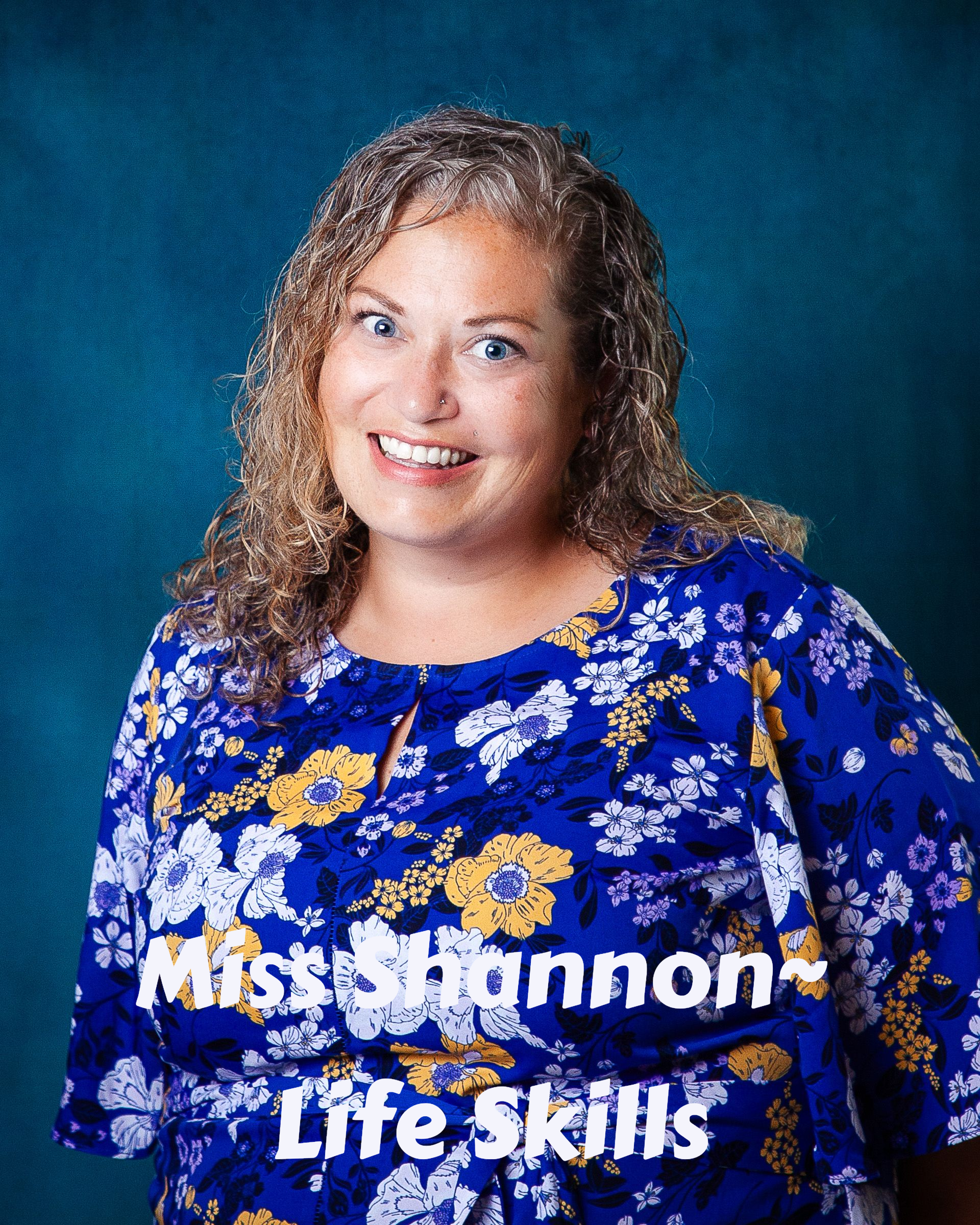 A woman with curly hair is smiling for the camera
