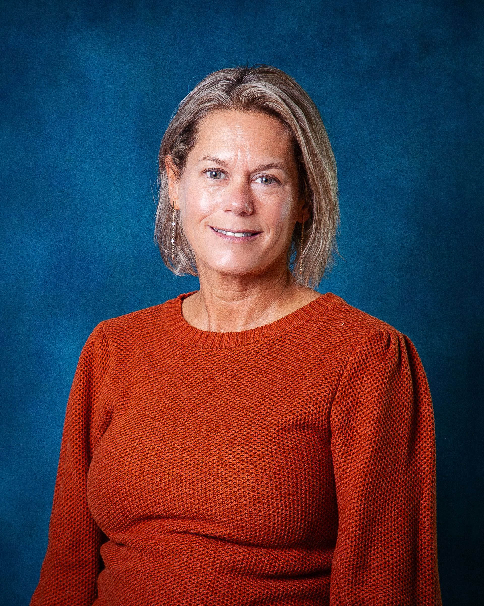 A woman in a green shirt is smiling for the camera.