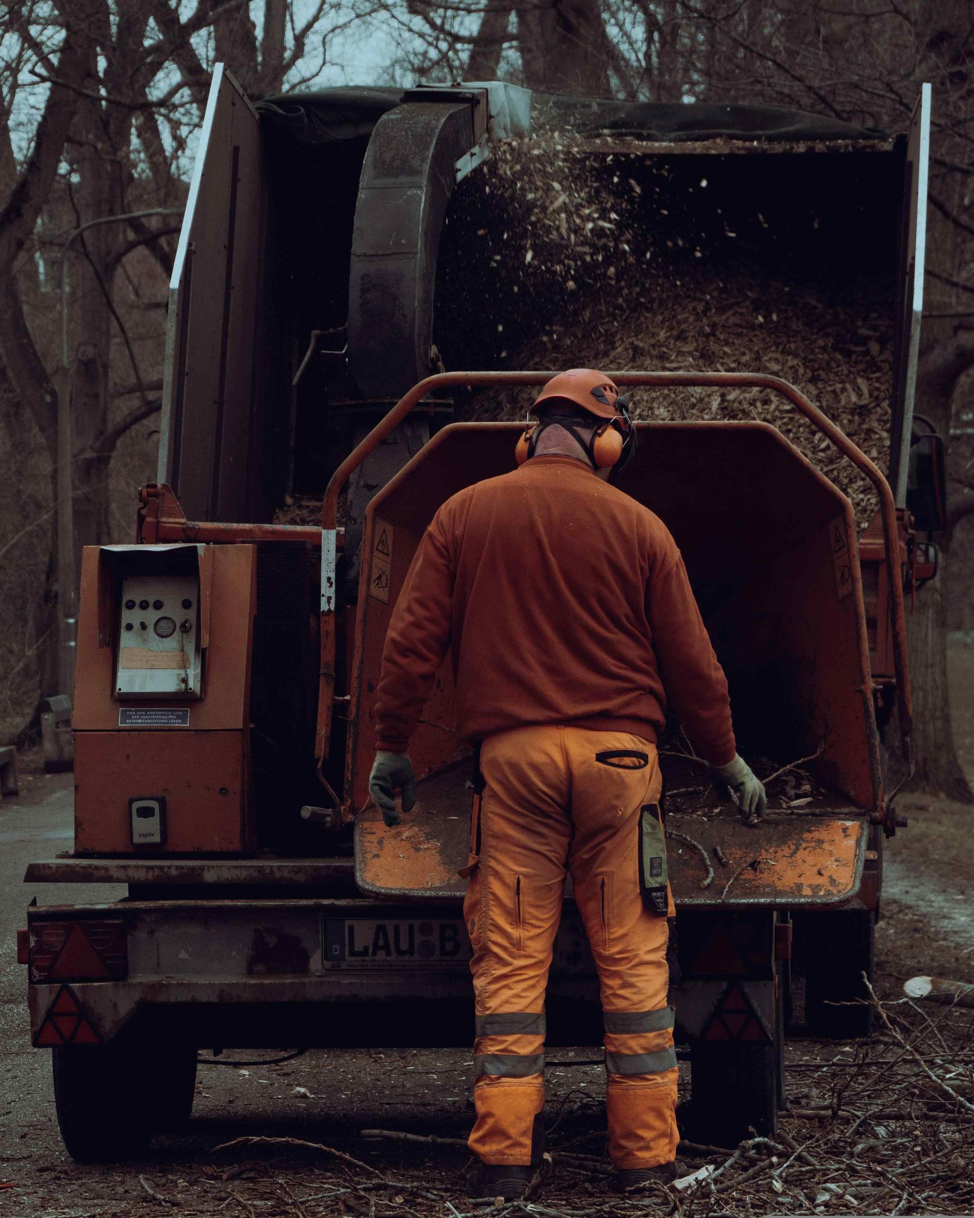 A man is standing in front of a tree chipper.