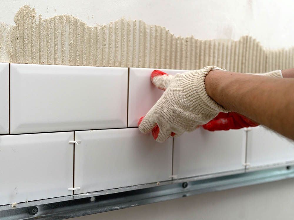 A person is installing tiles on a wall.