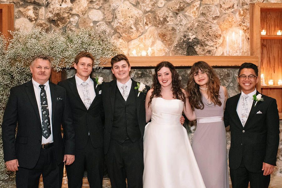 A group of people are posing for a picture at a wedding.