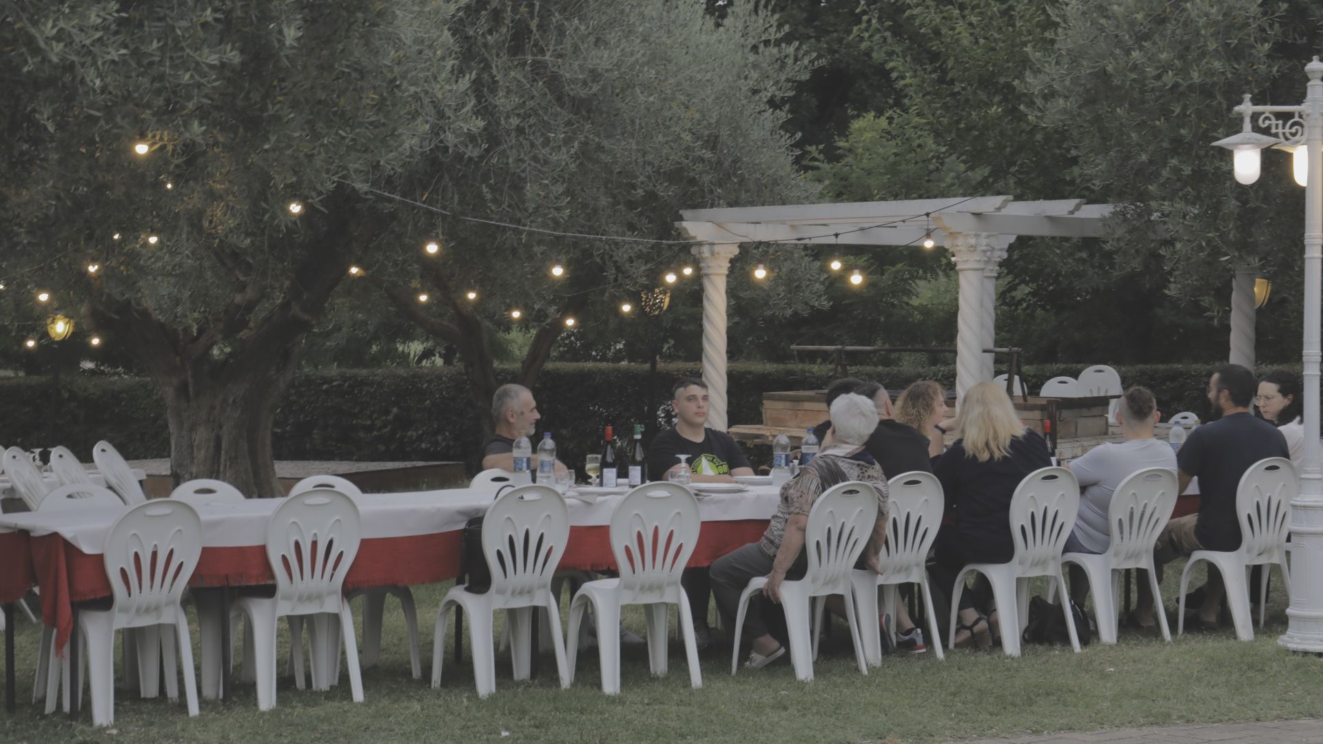 Lo chef in camice bianco e grembiule a righe sorride, seduto fuori.