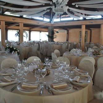 Lo chef in camice bianco e grembiule a righe sorride, seduto fuori.