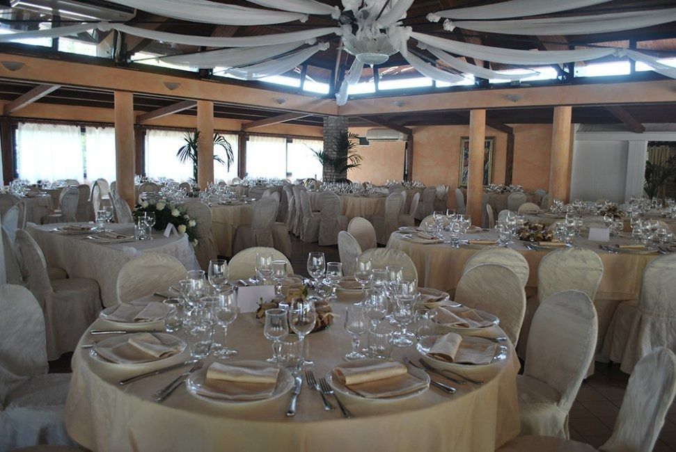 Lo chef in camice bianco e grembiule a righe sorride, seduto fuori.