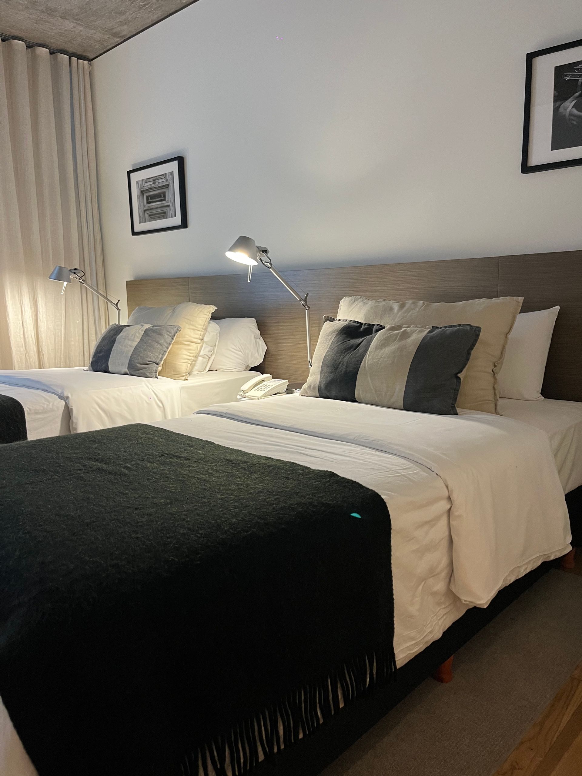 Una habitación de hotel con dos camas y una otomana negra